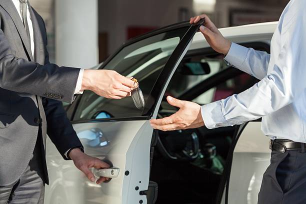 Salesman's hands giving key to male customer